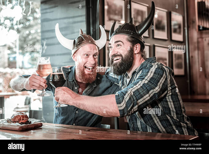 two-friends-wearing-viking-helmets-and-laughing-T7HW9P